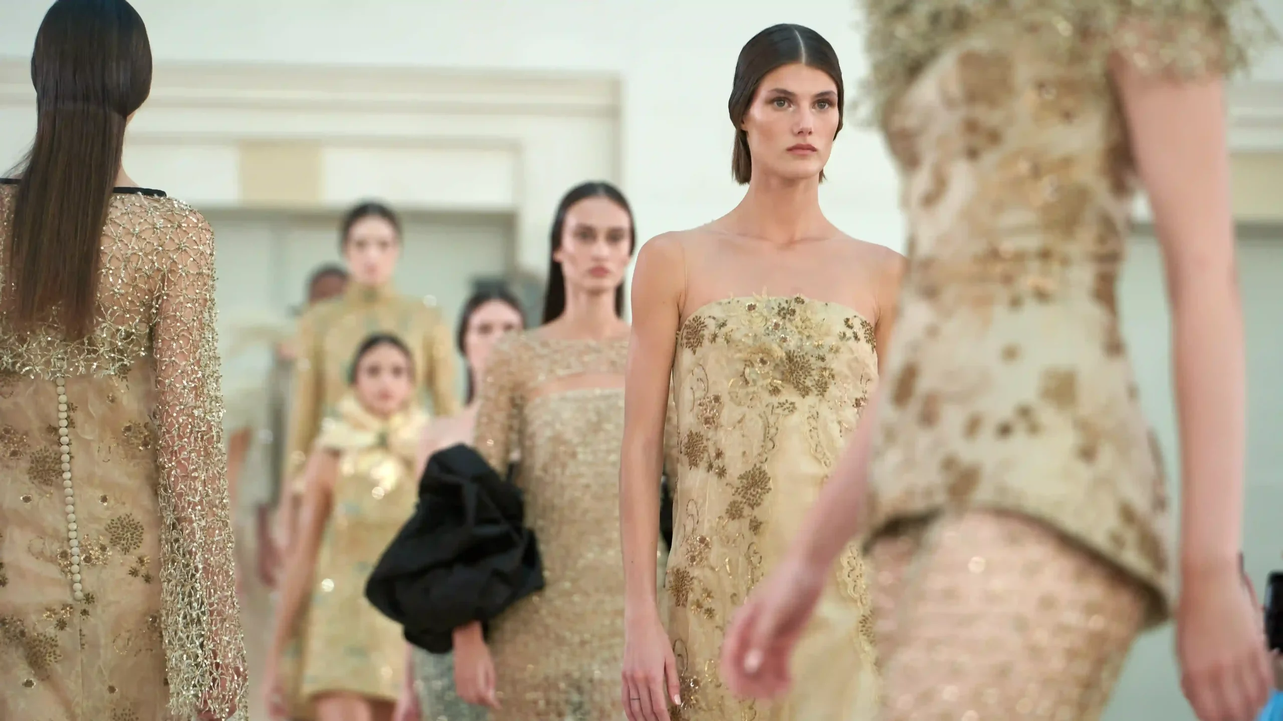 Modelos con vestidos dorados durante un desfile de moda